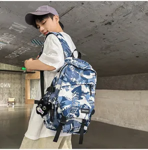 Detail eines Schülerrucksacks mit blauem Graffiti-Camouflage und Katzenanhänger