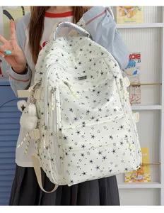 Vue détaillée du sac à dos blanc à motifs d'étoiles avec ours et breloques étoiles