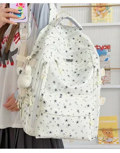 Gros plan d'un sac à dos blanc à motifs d'étoiles bleues avec breloque ours