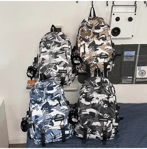 Vier Farbvarianten großer Camouflage-Graffiti-Rucksäcke mit Katzenanhängern im Zimmer.