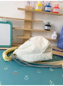 Dettaglio laterale della borsa a secchiello in nylon crema con tracolle multi-stile.