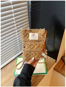 Handmade crochet crossbody phone bag with intricate hollow-out design and shell charms