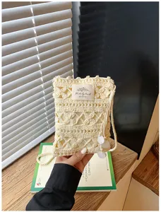 Detailed macro view of cream handmade crochet hollow phone bag with shell accents