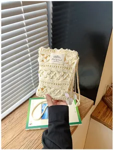 Close-up of handmade cream knitted crossbody phone bag with hollow-out pattern