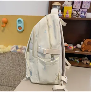 Seitenansicht eines süßen cremefarbenen Rucksacks mit blauen Schleifen für Schüler