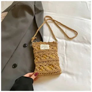 Close-up detail of a handmade khaki knit hollow-out crossbody cell phone bag on a blazer