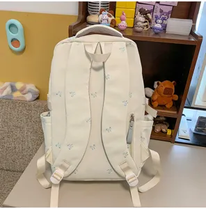Rückansicht eines niedlichen beigen Schulrucksacks mit blauen Schleifenstickereien