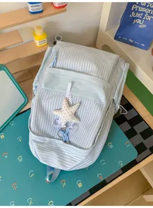 Nahaufnahme eines hellblau gestreiften Schülerrucksacks mit süßem Sternanhänger