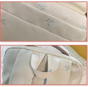 Detailansicht der blauen Schleifenstickerei und des stabilen Griffs am weißen Schulrucksack