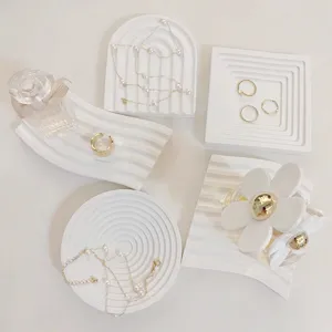 Detailed close-up showing various shapes of white ceramic display trays arranged flatly for photo styling.