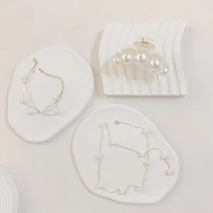 Elegant pearl hair claw clip and layered necklace jewelry set displayed on white aesthetic trays.