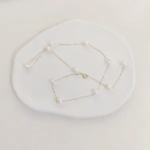 Elegant pearl gold chain detail shot, minimalist jewelry photography on white ceramic tray.