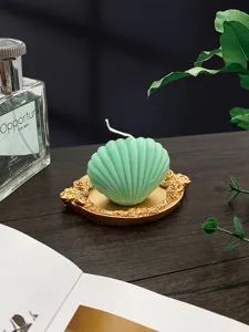 Close-up view of a green shell-shaped candle on an ornate gold tray, perfect home decor prop.
