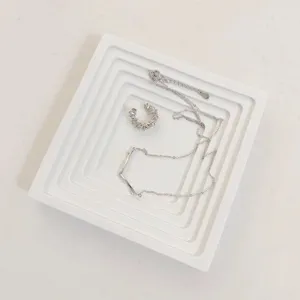 Silver-plated necklace and rhinestone ear cuff set displayed on a minimalist white tray.