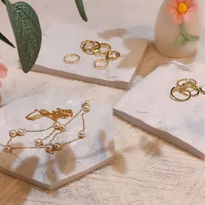 Close-up detail shot of white marble texture jewelry display tray with gold rings and pearls.