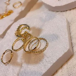 Gold ring set detail shot, featuring geometric twisted and minimalist bands on white tray.