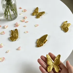 Dettaglio ravvicinato di magnete farfalla in resina dorata 3D, adesivo murale metallico.