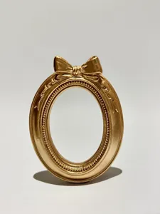 Vintage gold oval photo frame photography prop with bow for nail art and jewelry display details.
