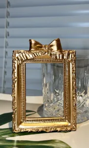 Retro gold mini photo frame prop, vintage bow design detail for jewelry and nail photography.