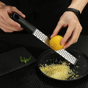 Stainless steel lemon zester and cheese grater detail in use, perfect kitchen tool.