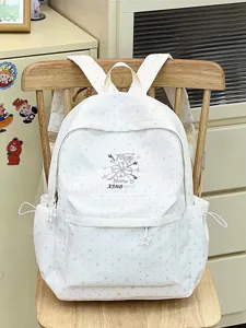 Detail eines weißen Schulrucksacks mit Sternen- und Punktmustern auf einem Stuhl