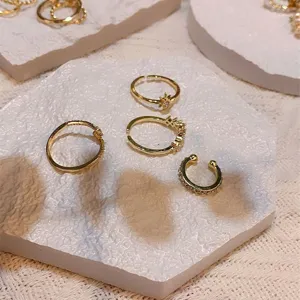 Gold rings and ear cuffs set displayed on white textured trays for chic photography props.