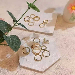 White marble texture jewelry display trays with elegant gold and pearl rings for desktop storage.
