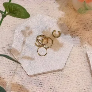 Gold ring and ear cuff jewelry set displayed on a white hexagonal tray for elegant showcase.