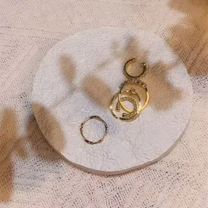 Gold ring set detail view featuring minimalist stackable rings and ear cuff on textured white tray.