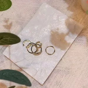 Detailed view of fashionable gold rings and ear cuffs displayed on a white textured tray.