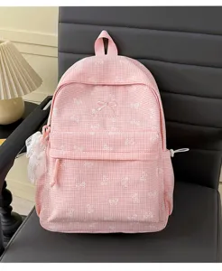 Gros plan d'un sac à dos à carreaux rose avec broderie nœud blanc et porte-clé en dentelle