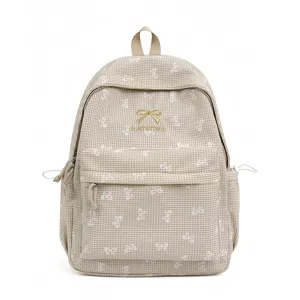 Détail de la broderie noeud et du logo AIYAYOU sur le sac à dos à carreaux beiges