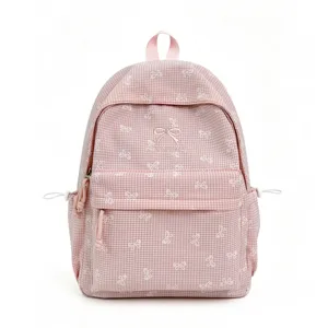 Gros plan d'un sac à dos d'écolier à carreaux roses avec broderie de nœud blanc