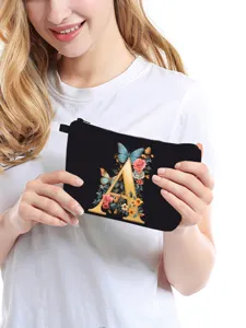 Dettaglio di una trousse nera con elegante stampa floreale della lettera A per viaggi