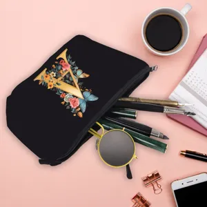 Beauty case nero con stampa floreale V, posizionato con cancelleria e occhiali da sole