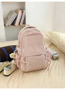 Détail d'un sac à dos rose pour étudiant avec broderie posé sur un lit douillet