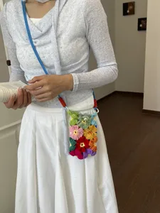 Sac de téléphone en crochet fait main avec fleurs colorées, style bohème porté épaule.