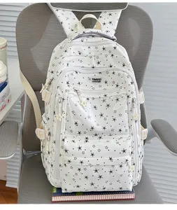 Détail de la vue avant d'un sac à dos blanc avec motif d'étoiles noires et poches.