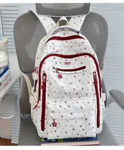 Détail d'un cartable blanc pour étudiants avec motifs d'étoiles rouges et fermetures éclair étoile.