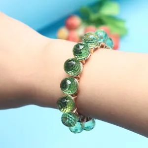 Closeup of the green faceted crystal bead bracelet on wrist, showing shiny details and texture.