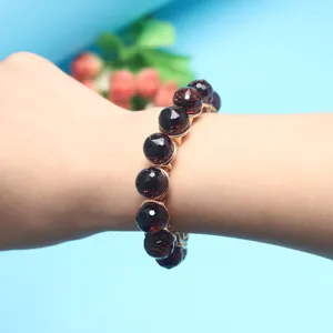 Close-up detail of faceted dark red crystal bead bracelet, elegant design, comfortable elastic fit.