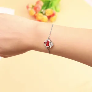 Elegant silver bracelet with red zircon heart and crown charm, adjustable chain design.