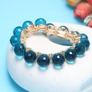 Close-up detail shot of a sparkling blue faceted crystal beaded stretch bracelet with gold settings.