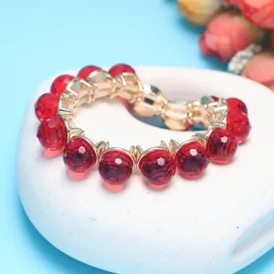 Detailed view of a stunning red crystal bead bracelet with gold accents on a white display.