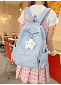 Mochila azul claro con estampado de corazones y colgante de estrella en una modelo