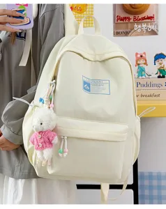 Primo piano di uno zaino scolastico color crema con un simpatico ciondolo a pecora rosa