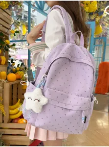 Vista detallada de una mochila escolar morada con corazones plateados y peluche de estrella