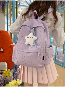 Vista detallada de una mochila escolar lila con corazones y un dije de estrella de peluche.
