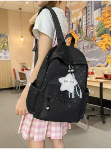 Mochila escolar negra con patrones de corazones y un dije de estrella de felpa blanca