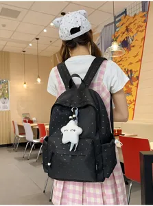 Vista trasera de mochila negra con patrón de corazones y lindo colgante de estrella